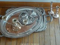 Photo showing all items on a wooden floor including two trays, the cream and sugar set on the smaller tray, two single candlestick holders, and a three-candle candelabra.