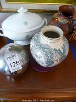 Photo of tureen with lid, ceramic vase with blue floral pattern, metal ice bucket with lid, and hand-painted ceramic pitcher with grapevine and leaf design.