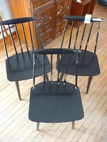 Three Danish wood chairs painted black arranged on wood floor, showing overall condition and style.
