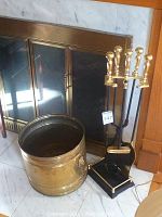 Full view of brass firewood storage bucket and fireplace tool set with stand, showing brass and black finish with four tools and bucket.