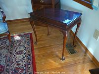 Full side and front angle view of the rectangular mahogany side table with curved legs on a hardwood floor.
