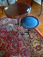 Two pie crust tables on a patterned rug, showing taller table with scalloped top and pedestal base, next to shorter table with blue tray top.
