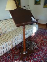 Front view of the wooden music stand showing its curved top and turned central support column.