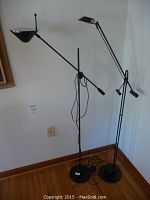 Two black metal adjustable floor lamps side by side showing full height and base design.