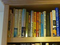 Top shelf of three wooden shelves filled with humor books. Visible titles include humor and comedic fiction authors.