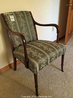 Front angle view of the dark wood and upholstered armchair showing fabric pattern and armrest design.