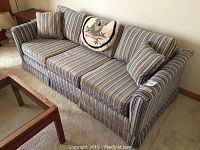 Front and side view of the striped sleeper sofa with cushions and owl throw pillow, showing overall shape, fabric pattern, and condition.