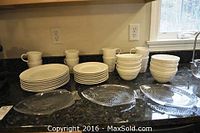 White ceramic plates, bowls, and mugs with three clear glass fish dishes in front