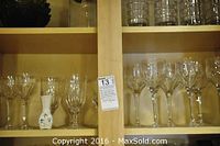 Glass cabinet shelf with various crystal wine glasses and small ceramic vase inside