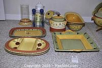 Photo showing various Pistoulet pattern ceramic serving pieces including square platter, divided and oblong platters, deep bowls, and covered jar with olive motif and yellow-green border