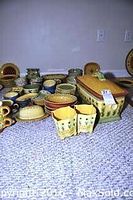 Full view of over 30 pieces of Pfaltzgraff stoneware set with plates, bowls, mugs, bread bin, custard cups, and more.