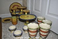 Photo of full set showing five cake stands, one platter, five custard cups, and other pieces arranged together on floor.