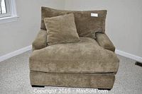Front view of oversized mushroom brown micro-suede chair with deep cushions and matching pillow on carpeted floor.