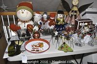 Wide shot showing assorted Christmas decor items including figurines and decorative plates displayed on a shelf