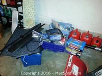 Overview of lot showing gas cans, car mats, storage containers with accessories, and outdoor tools