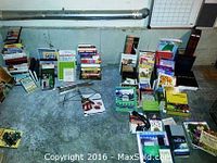 Wide view showing over 40 assorted books arranged on floor, metal sheet music stand, and an L.L.Bean headlamp