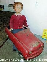 Pedal car in red metal with doll seated to illustrate scale and condition
