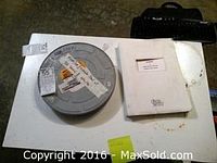Top view of the metal 35mm film reel and the white folder containing the script alongside a small black case.