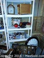White shelving unit displaying the Ethan Allen wall clock on bottom shelf leaning against the shelf, vintage printers drawer on top shelf, and various decorative items such as a black and white framed photo, small ceramic bowl, and candles on other shelves.