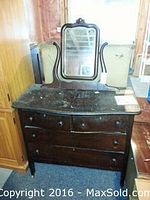 Photo of hardwood dresser with attached swiveling vanity mirror; top surface heavily damaged, dark wood with four drawers and round wood knobs