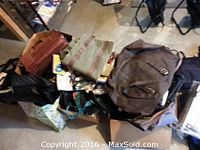 Overhead view showing a pile of assorted bags including backpacks, totes, and soft luggage in various earth tones.