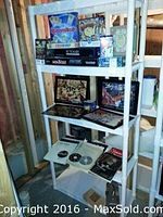 Shelving unit holding board games, puzzles, DVDs, and framed prints; clear view of upper two shelves with various game boxes including Rummikub, Monopoly, and Pictionary