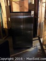 Mini fridge from front with closed door in wooden frame background
