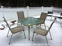 Full set of outdoor furniture including square glass top table, matching armchairs, beverage tables, camping chairs, and additional chairs on a snow-covered patio