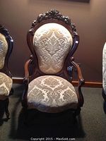 Front view of armchair showing carved floral crest and upholstery