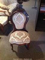 Front view showing carved floral crest, balloon back and damask upholstery pattern