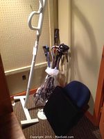 White floor-to-ceiling pole with hand grips, collection of canes and walking sticks alongside blue back rest and black wedge pillow