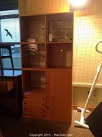 Closed view of two-piece IKEA display cabinet in light wood finish with glass doors and drawers