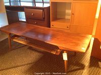 Full view of coffee table showing top, legs and lower wicker shelf