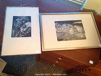 Both framed prints side by side on wooden table