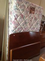 Double bed headboard and footboard leaning against the wall with mattress behind them.