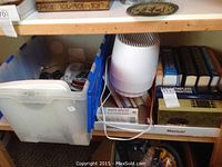 Shelf containing assorted books, Honeywell humidifier, and miscellaneous items including telephones.