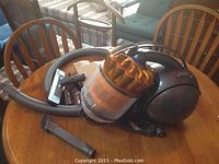 Front view of Dyson canister vacuum and attachments on table