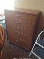 Front view of five-drawer wooden highboy dresser with metal handles, showing overall condition and finish.