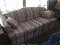 Front-side view of the sofa with two matching throw pillows showing the striped and floral upholstery pattern.