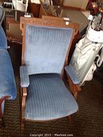 Front view of the rocking chair showing blue ribbed upholstery with carved wooden frame
