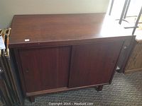 Front view of rectangular mahogany cabinet with two sliding doors closed, showing wood grain and surface wear.