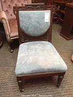 Front view of the occasional chair showing blue fabric upholstered seat and front leg with caster.