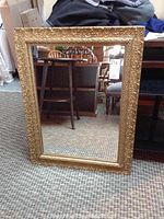 Rectangular mirror with ornate gold painted wood frame, showing overall decorative detail and minor damage