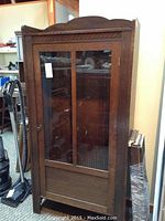 Full front view of oak cabinet with glass door and carved trim