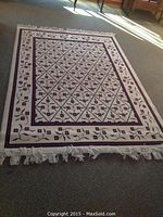 Full view of rectangular rug showing pattern and fringed edge.