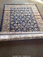 Full view of the Caspian Persian-style rug showing the dark blue floral central field and cream border.
