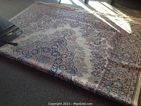Full view of the machine made 8'x11' area rug showing overall pattern and condition with some sunlight glare.