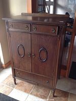 Front three-quarter view of dark wood dresser showing two top drawers, two centre doors and lower drawer.