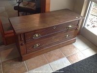 View of oak chest showing top, sides, and front with two drawers and decorative brass handles.