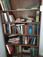 Full bookshelf with various books including older hardcovers, paperbacks, and some binders/folders
